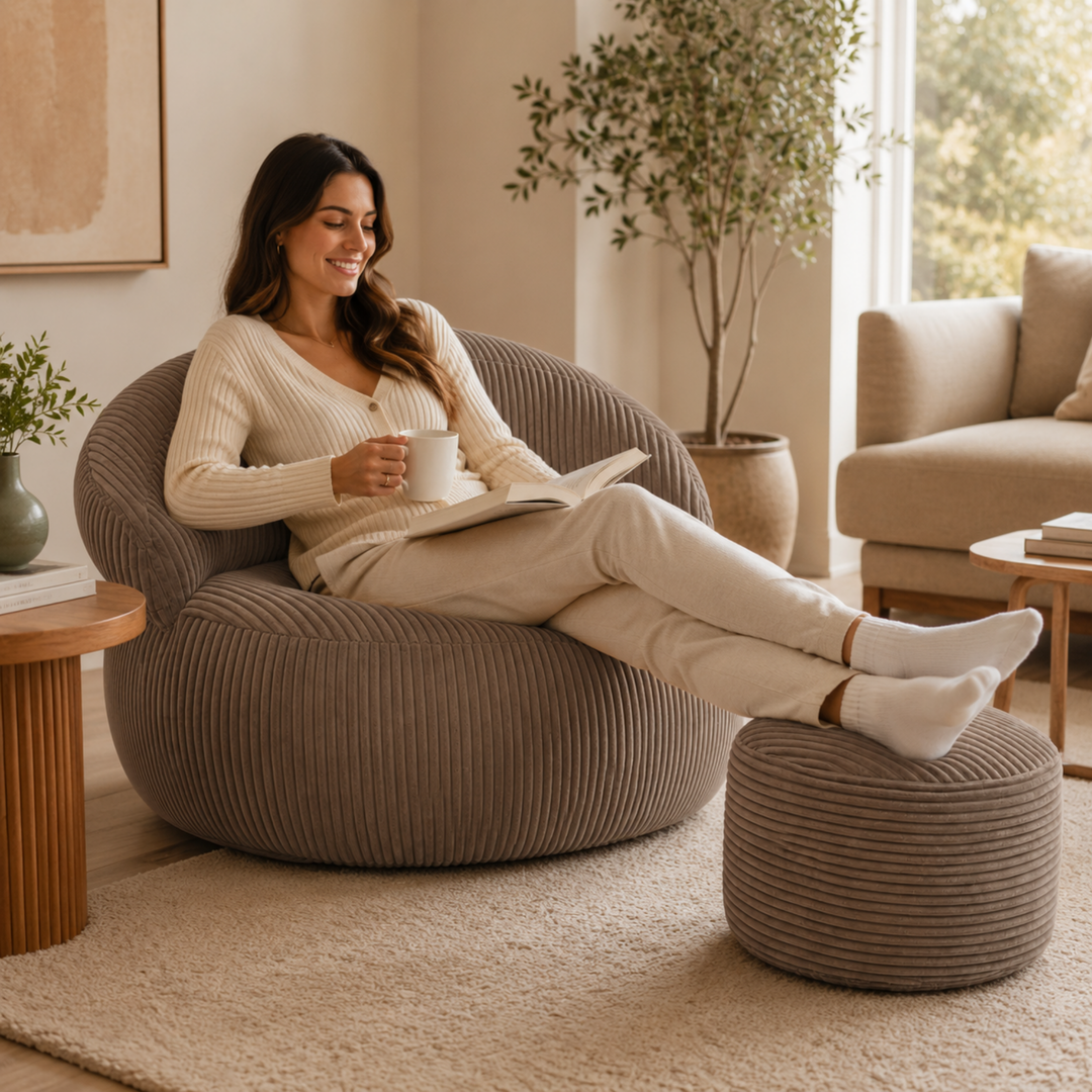 Personne assise confortablement sur un pouf XXL en velours côtelé avec repose-pieds, dans un salon