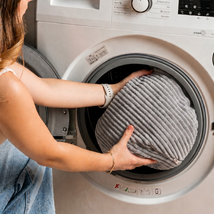Housse grise de chauffeuse d’appoint placée dans un lave-linge
