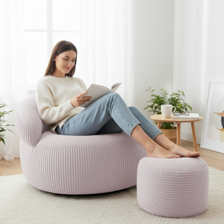 Personne assise confortablement sur un pouf XXL en velours côtelé avec repose-pieds, dans un salon