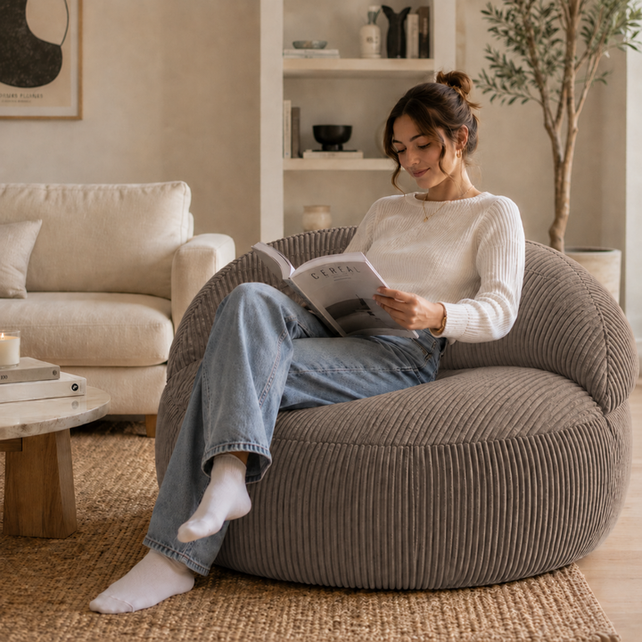 Personne assise sur un pouf XXL en velours côtelé, dans un salon