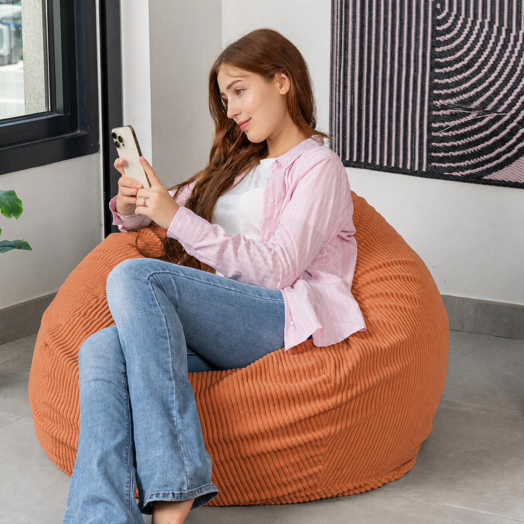 Femme assise sur un pouf poire déhoussable en velours côtelé, dans un salon