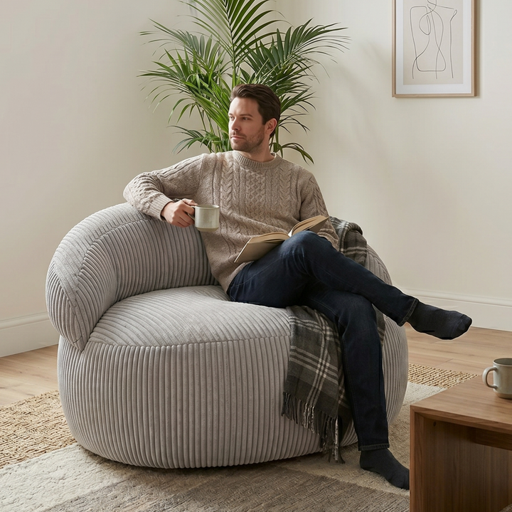 Personne assise sur un pouf XXL en velours côtelé, dans un salon