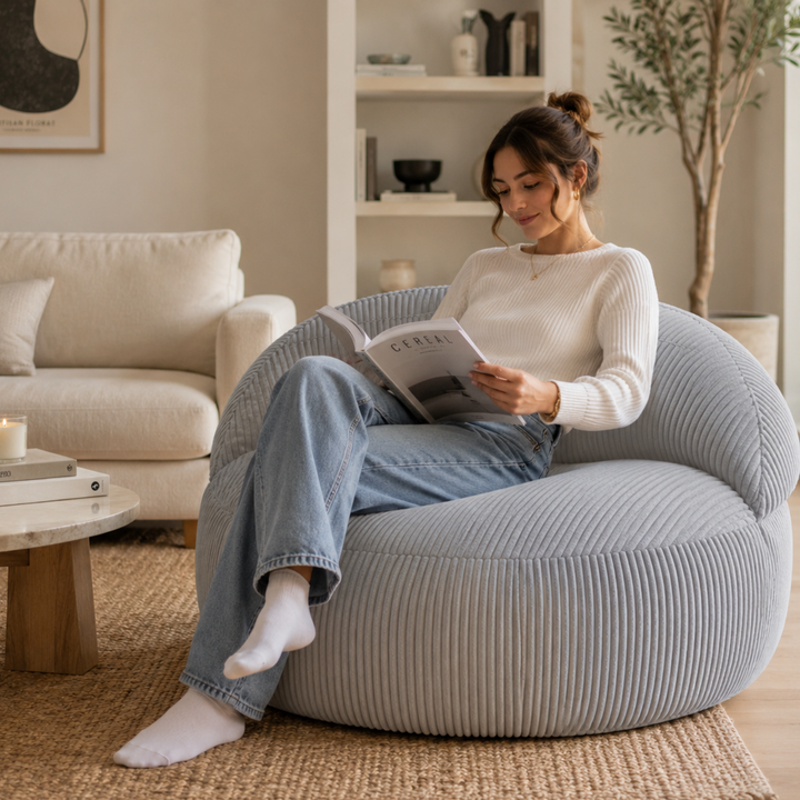 Personne assise sur un pouf XXL en velours côtelé, dans un salon