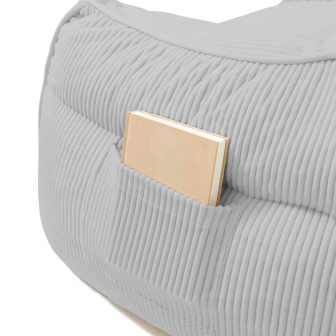 Pouf fauteuil en velours côtelé gris clair, détail de la poche de rangement sur le côté.