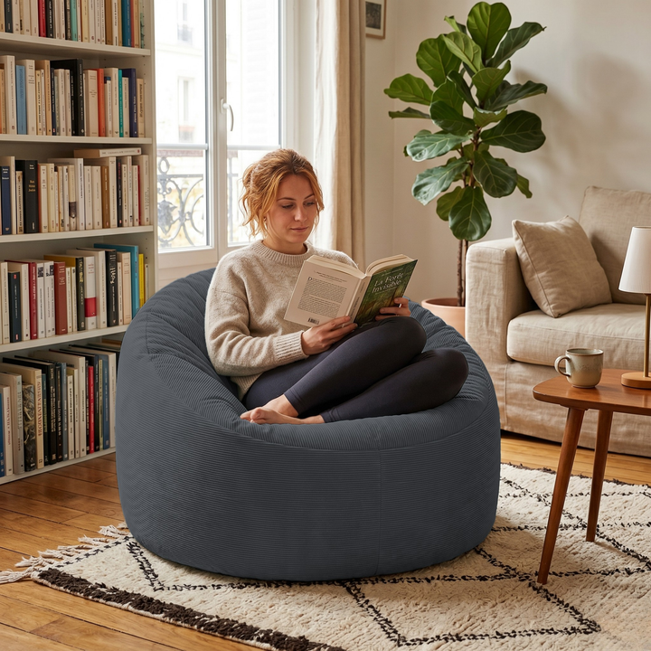 Personne assise dans un pouf rond en velours côtelé, dans un salon