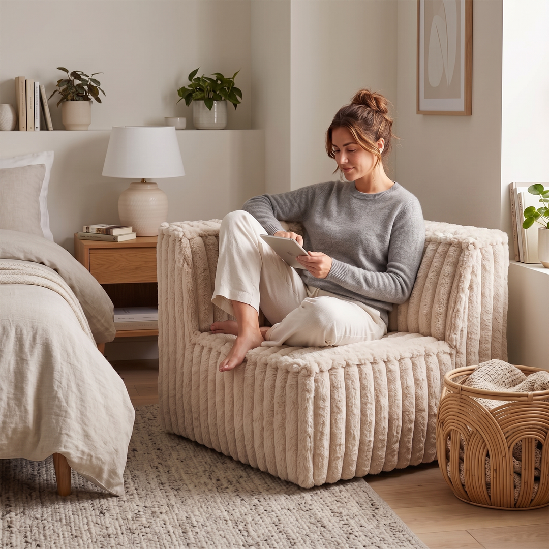 Femme assise dans un module d’angle gauche déhoussable en fourrure côtelée beige.